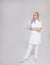 Full length portrait of female doctor, nurse or cosmetologist in white uniform thinking about something over gray background with