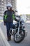 Full length portrait of female motorcyclist in safety outfit standing near classic bike on urban road