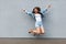 Full length portrait of free happy beautiful woman in casual jeans denim style in summertime jumping at light blue wall, having