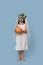 Full-length portrait of a girl with a pumpkin in a costume of a dead bride