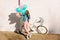 Full-length portrait of girl in stylish pink pants and denim jacket making selfie in front of white bicycle. Bicyclist
