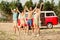 Full length portrait of group satisfied peaceful fellows hold raise arms standing sand beach enjoy pastime outside