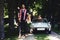 Full length portrait of handsome brunette man standing against luxury cabriolet car at countryside