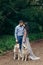 Full-length portrait of the happy adorable elegant couple with two huskies during their walk in spring park. Woman in