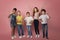 Full length portrait of happy diverse schoolkids making different gestures on pink background