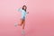 Full-length portrait of inspired dark-haired woman in blue shirt jumping and laughing during photoshoot. Glad hispanic