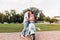 Full-length portrait of kissing couple holding hands with tenderness near scooter. Outdoor photo of blissful young