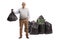 Full length portrait of a mature man holding a waste bag near a pile of bags and a bin