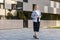 Full length portrait of positive businesswoman holding phone, walking near futuristic office building. business style