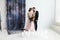 Full-length portrait of pretty newlyweds with bouquet. isolated white background and blue curtain. Studio horizontal
