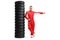 Full length portrait of a racer leaning on a pile of tires and pointing to the side