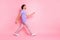 Full length portrait of satisfied person walking free time watch empty space magenta shirt isolated on pink color