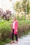 Full length portrait of serious beautiful young successful businesswoman in elegance style standing on green park, posing with