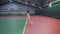 Full length portrait of slim woman in sport outfit playing tennis at indoor court with professional equipment