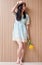 Full length portrait of smilimg asian girl holding bouquet with yelliow flowers against wood wall