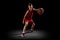Full-length portrait of teen boy, professional backetball player in motion, training isolated over black background