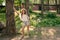 Full-length portrait of tween girl leaning of tree in courtyard of country house in summer