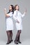 Full-length portrait of two female doctors standing back-to-back hold ready-to-inject syringes
