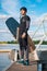 Full length portrait of wakeboarder with board in hand standing on pier