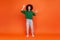 Full length portrait of woman with Afro hairstyle wearing green casual style sweater standing with