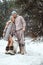 Full-length portrait of a young beautiful couple of European appearance with a husky dog in the winter forest