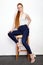 Full length portrait of young beautiful redhead beginner model woman in white t-shirt blue jeans practicing posing showing emotion