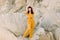 Full length portrait of a young dark haired tall model girl in fashionable yellow overalls posing in sand quarry