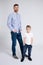 Full length portrait of young father and little son posing over white