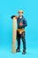 Full length portrait of young handsome carpenter showing thumbs up sign holding pile of lumber woods and