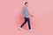 Full length portrait of young handsome guy go walk step happy positive smile isolated over pink background