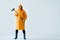 Full length portrait of young handsome man in bright raincoat holding big axe