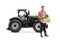 Full length portrait of a young man with a tractor holding a crate full of fresh vegetables