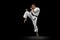 Full-length portrait of young sportsman training karate isolated over black background. In motion