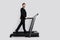 Full length profile photo of classy sporty man walk treadmill empty space proposition isolated on grey color background