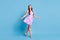 Full length profile photo of pretty girl walk shiny smile wear violet dress stilettos isolated blue color background