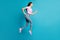 Full length profile photo of sportive cute girl jump run look empty space wear pink t-shirt sneakers jeans  blue