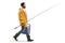 Full length profile shot of a fisherman in a raincoat walking and carrying a portable fridge and a fishing rod