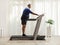 Full length profile shot of a mature man pushing a power switch on a treadmill