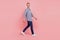 Full length profile side portrait of young handsome guy go walk step happy positive smile isolated over pink background