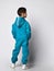 Full length rear view of a little preschooler or schoolboy in a warm blue sports suit.