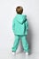 full-length rear view of a little preschooler or schoolboy in a warm turquoise tracksuit with a hood and white sneakers