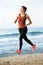 Full length serious female runner on beach for fitness routine