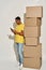 Full length shot of busy male professional mover in casual wear using smartphone, standing near a stack of cardboard