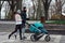 Full length shot of motivated sportive family in sportswear running together with a pram along an empty park on a cold