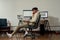 Full length shot of relaxed young male trader holding papers with statistics while talking on the phone, sitting at desk