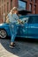 Full length shot of young woman opening the blue car door while holding grocery bag after shopping in the supermarket