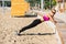Full length side view of a adorable fitness girl doing push ups at the beach
