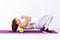Full length side view athletic woman training on yoga mat using foam roller massager under shoulders, stretching spine muscles,