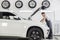 Full length side view of male mechanic examining car engine in repair shop