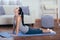 Full length side view portrait of beautiful young woman working out at home, doing yoga or pilates exercise on wooden